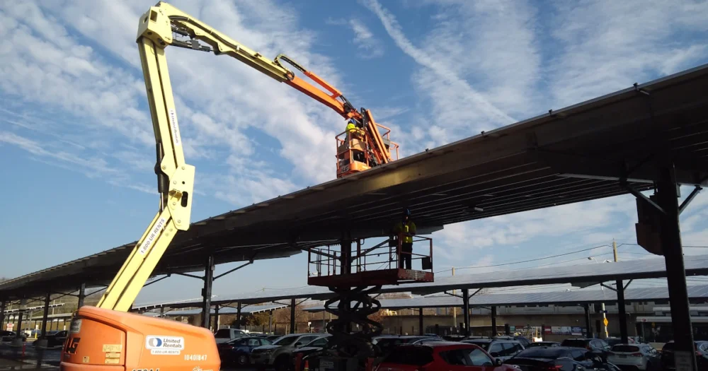Byggarbetare i bomliftar arbetar med solpaneler vid en station
